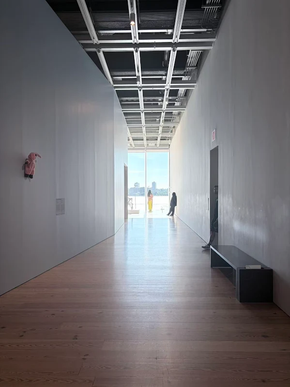 A gallery corridor with a bright window at the far end.