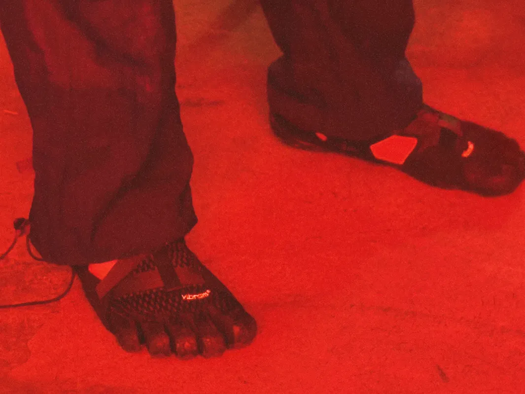 Feet in toe shoes on a floor washed in red light.